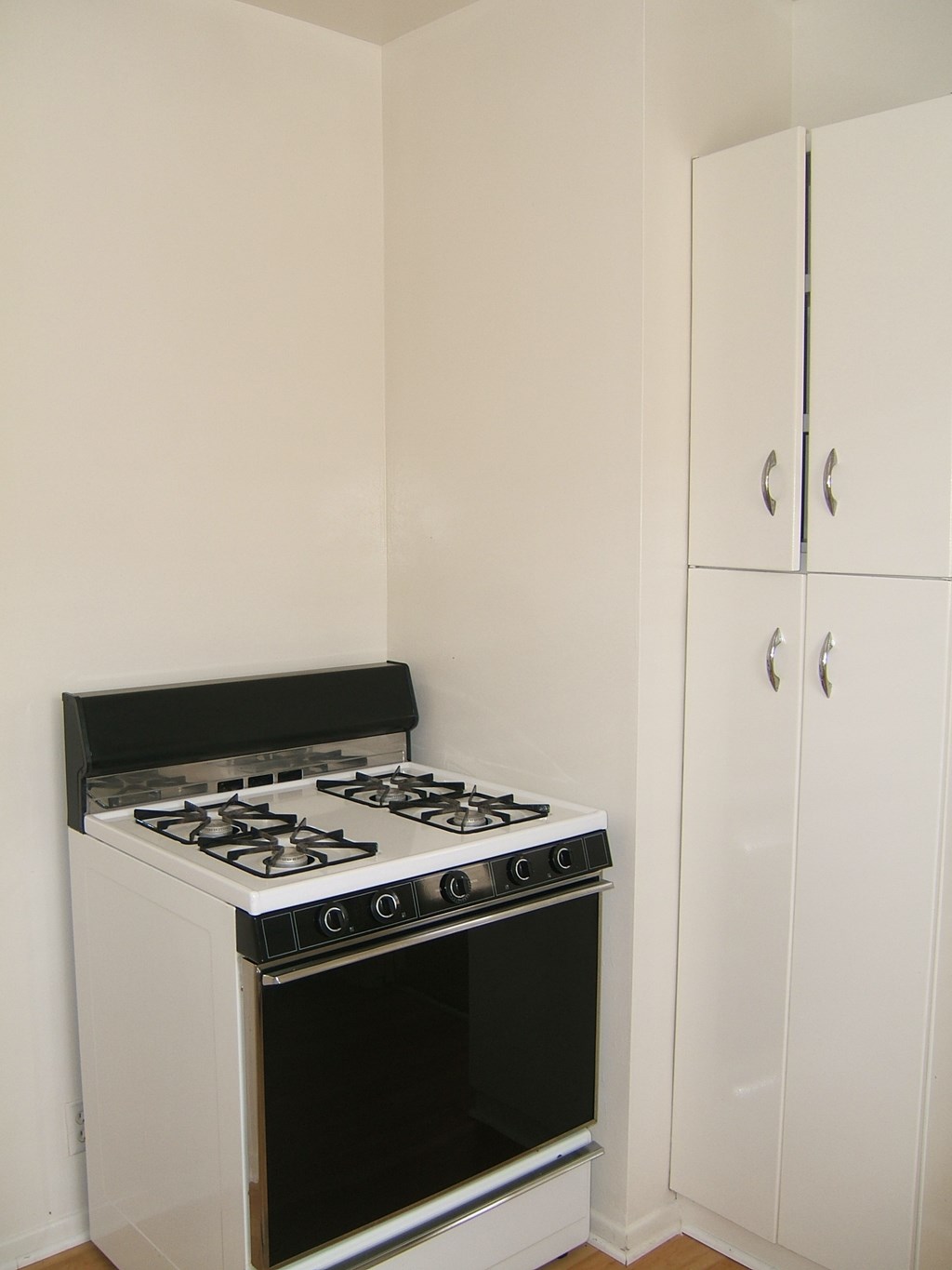 a small kitchen with white cabinets and a stove top oven