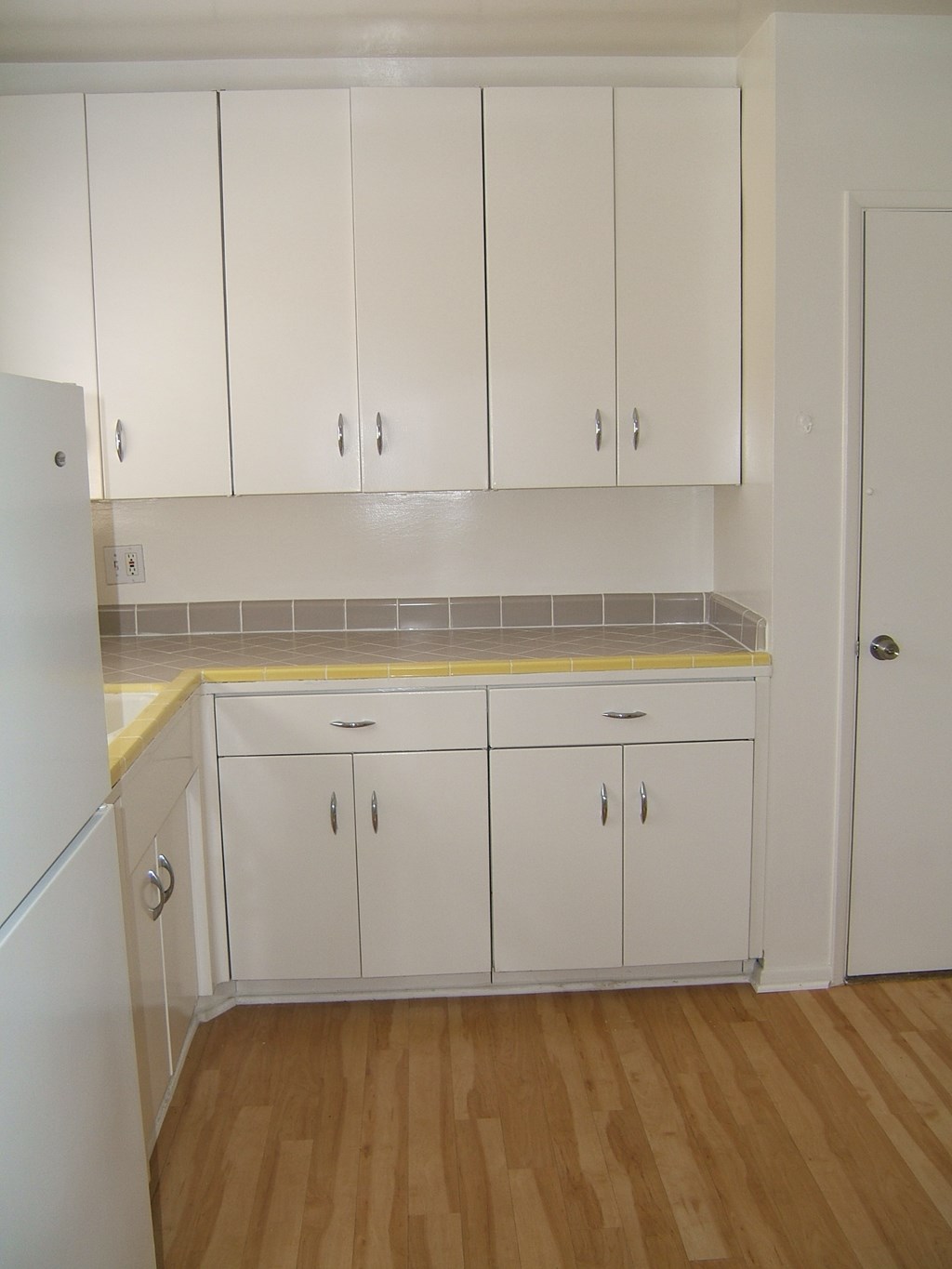 an empty kitchen with white cabinets and a wooden floor