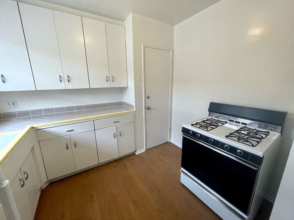 an empty kitchen with a stove and white cabinets