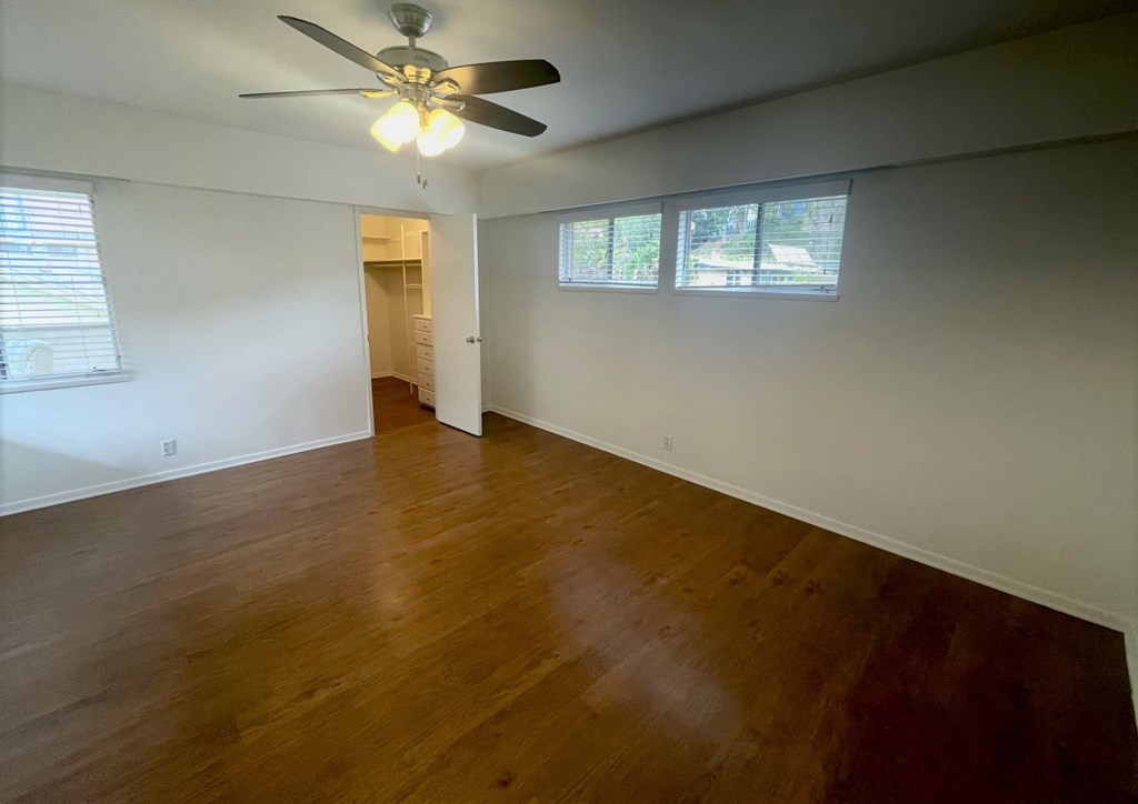 an empty living room with wood floors and a ceiling fan