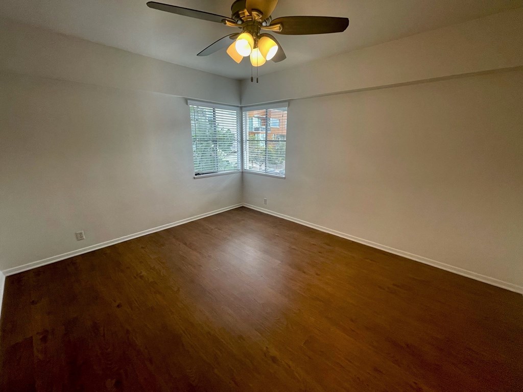 an empty living room with wood floors and a ceiling fan