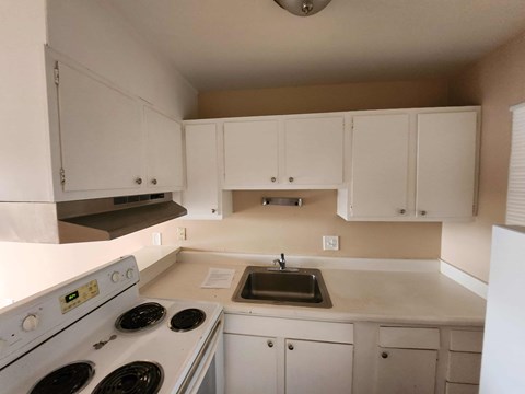 A kitchen with white appliances and cabinets.