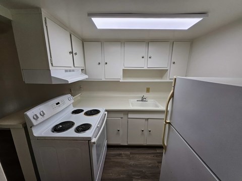 A small kitchen with white cabinets and a stove top oven.