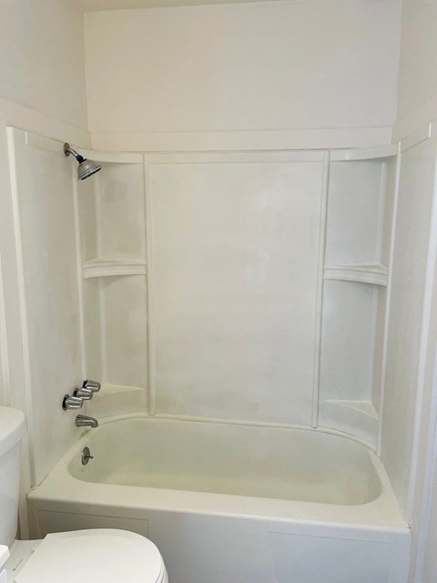 A white bathroom with a toilet, tub, and shower.