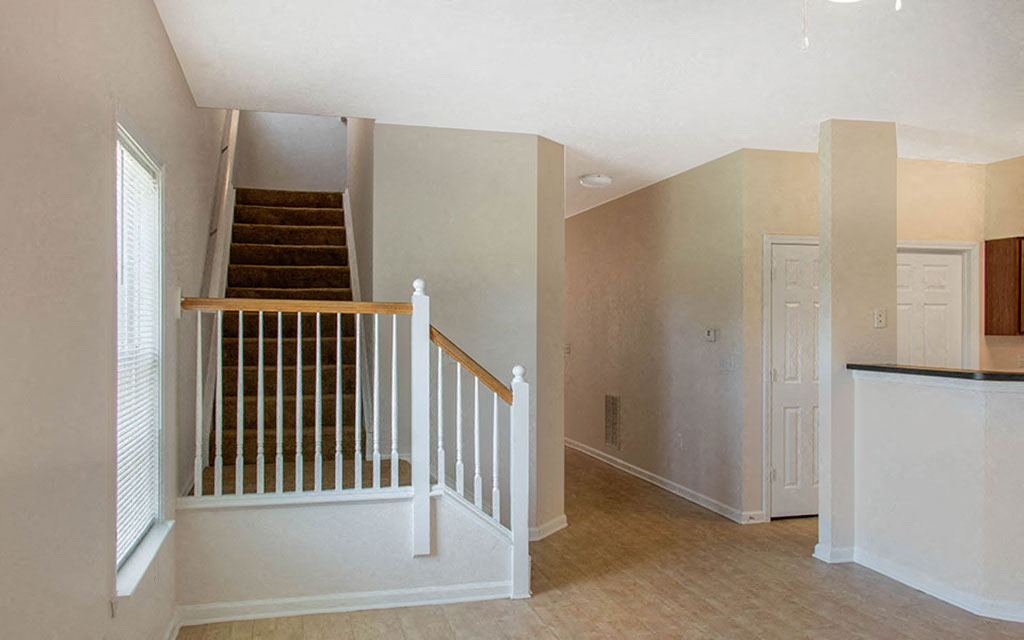 an empty house with a staircase and a white staircase
