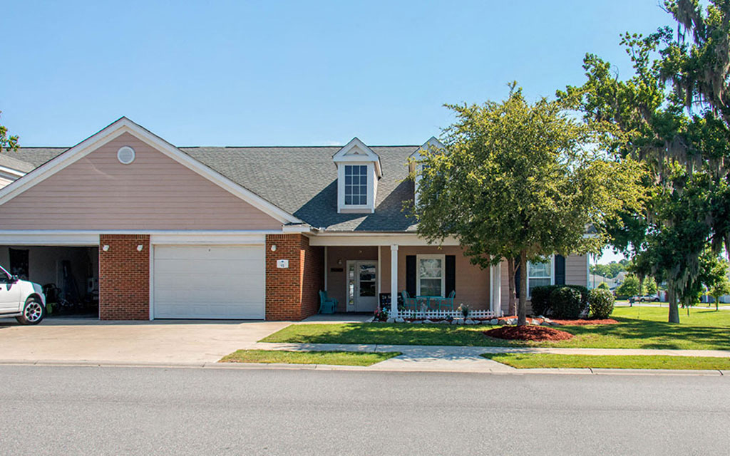 a house with a porch and a tree in front of it