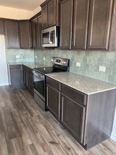A kitchen with dark wood cabinets and a granite countertop.