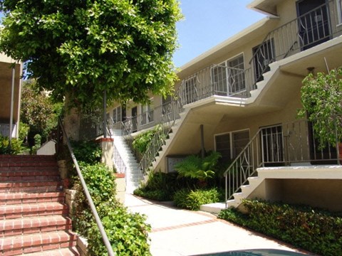 A building with a staircase and a tree in front of it.