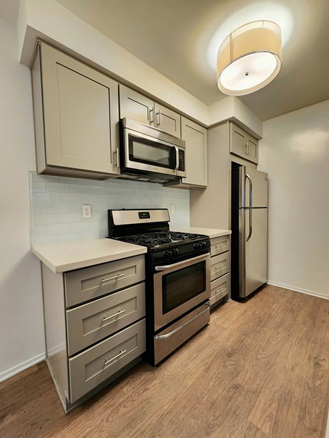 A kitchen with a stove top oven, microwave, and refrigerator.