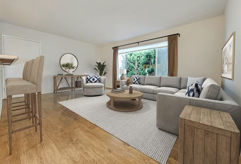 A living room with a grey couch, a wooden coffee table, and a round mirror on the wall.