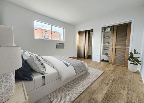 A bedroom with a large bed and a wooden floor.