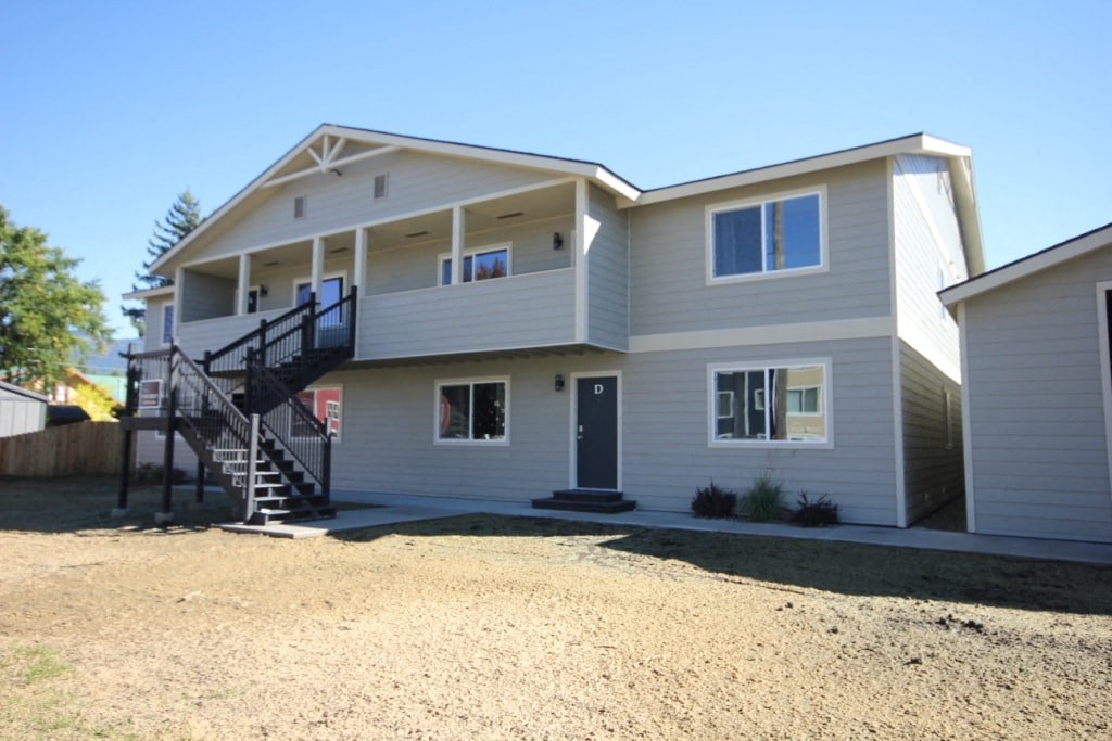 the front of a white house with a black staircase