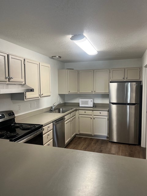 an empty kitchen with white cabinets and stainless steel appliances