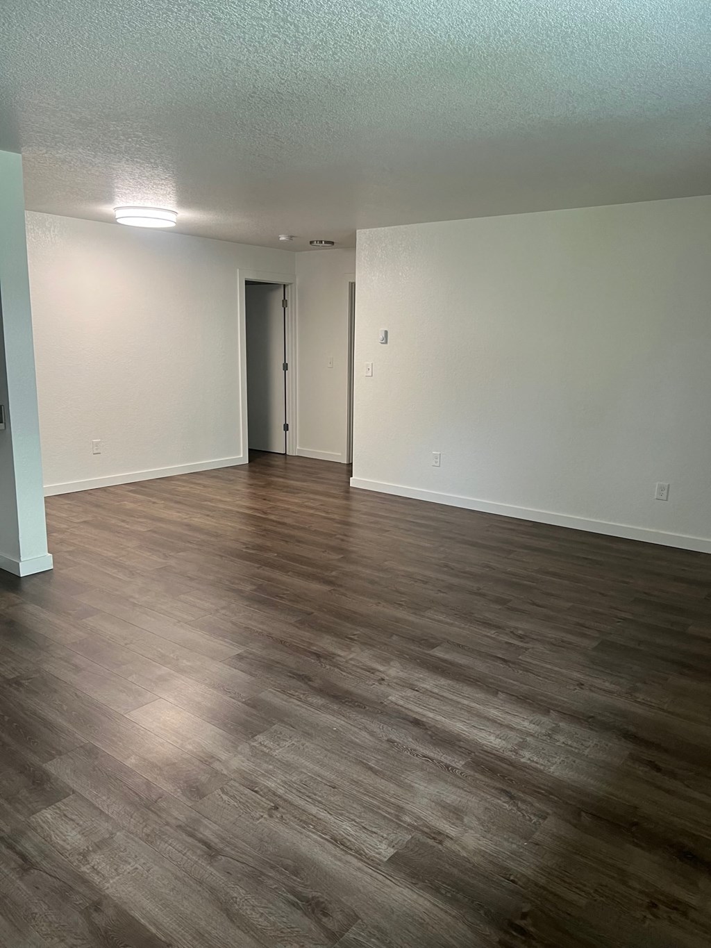 an empty living room with wood floors and white walls
