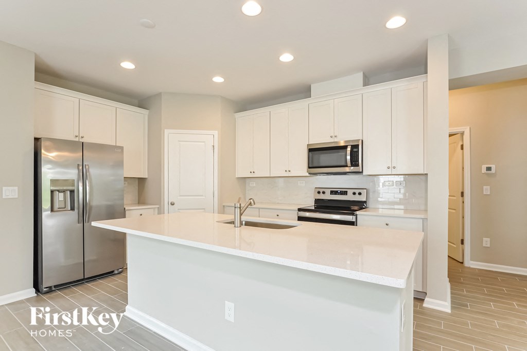 a white kitchen with a large island and stainless steel appliances