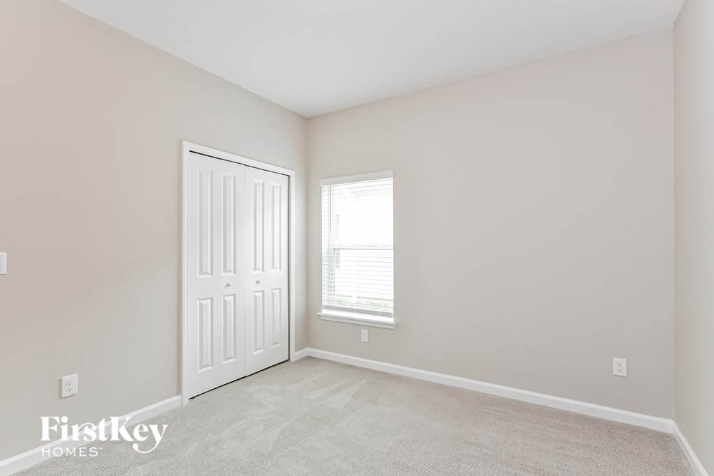 a bedroom with a white door and a window and a carpeted floor