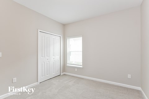 a bedroom with a white door and a window and a carpeted floor