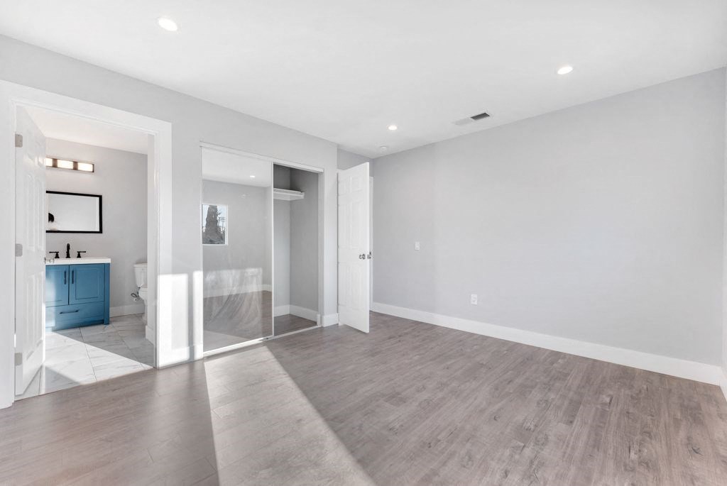 an empty living room with a bathroom in the background