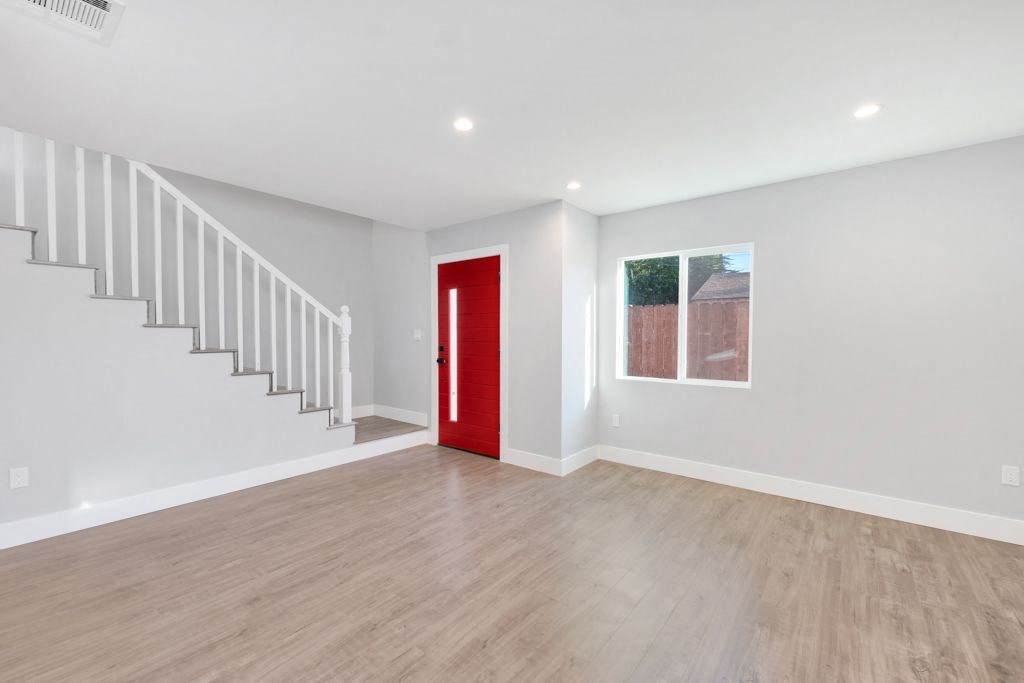 a white room with a red door and a staircase
