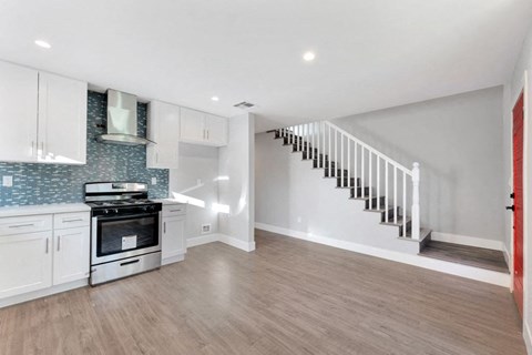 a kitchen with white cabinets and a stove and a staircase