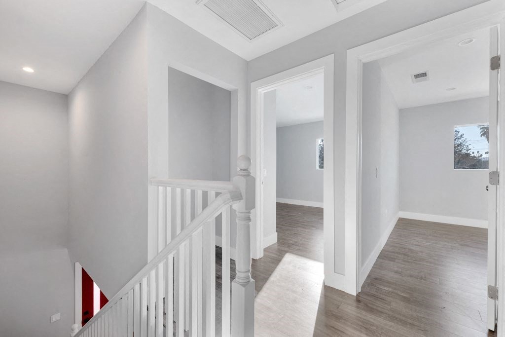 a white staircase with a view of a hallway and a living room