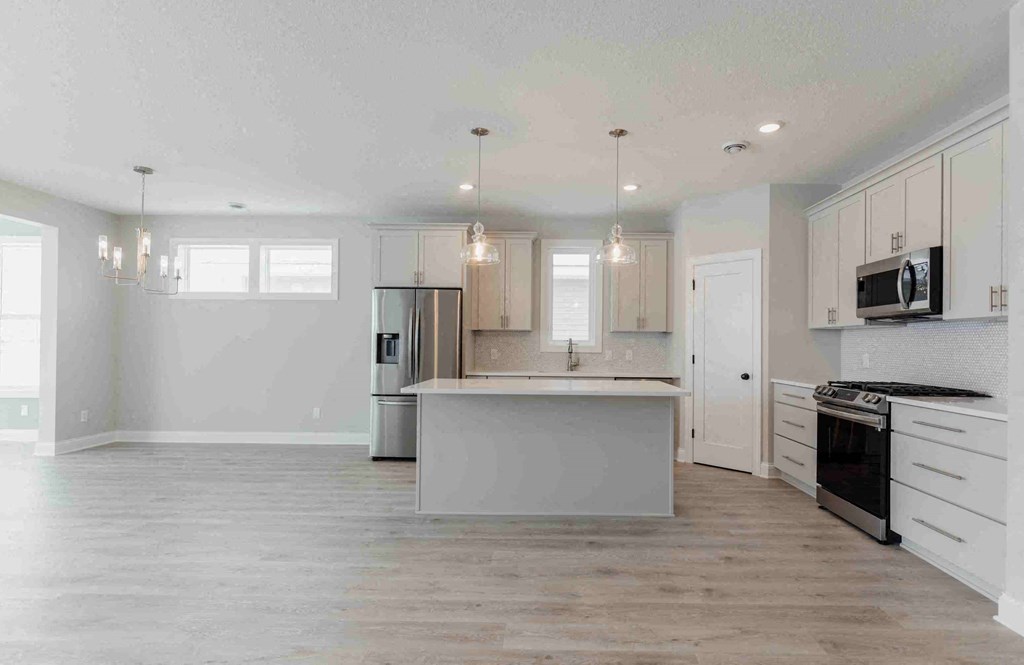 a white kitchen with a large island in the middle