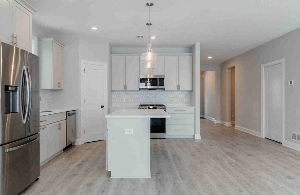 an open kitchen with white cabinets and stainless steel appliances and a island