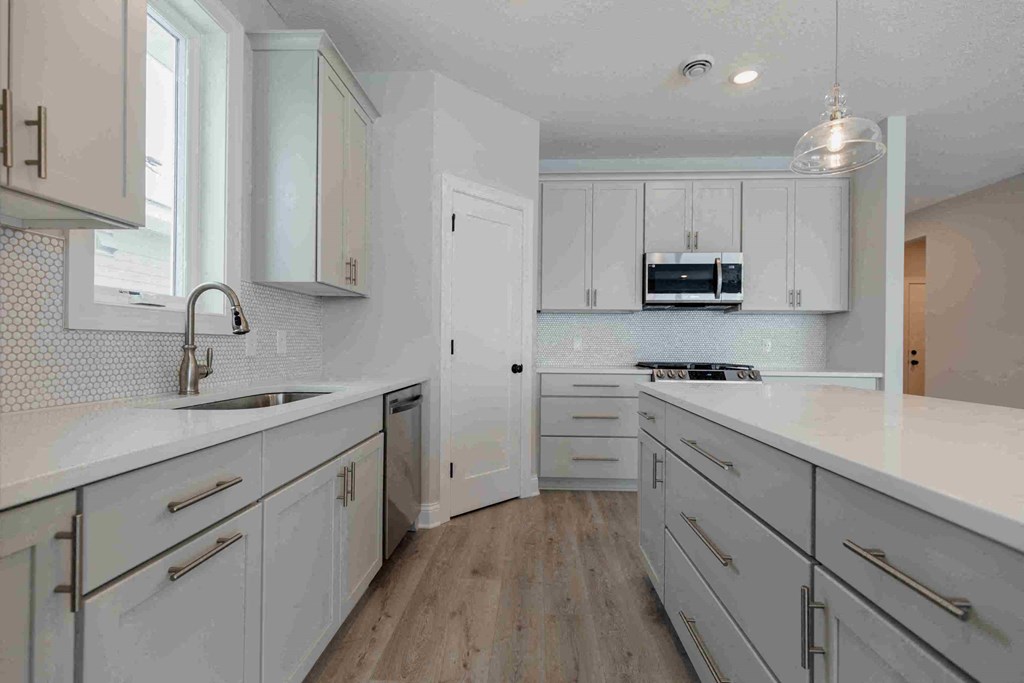 a white kitchen with white cabinets and a sink