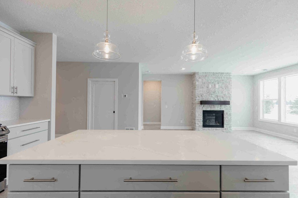 an empty kitchen with a white counter top and a fireplace