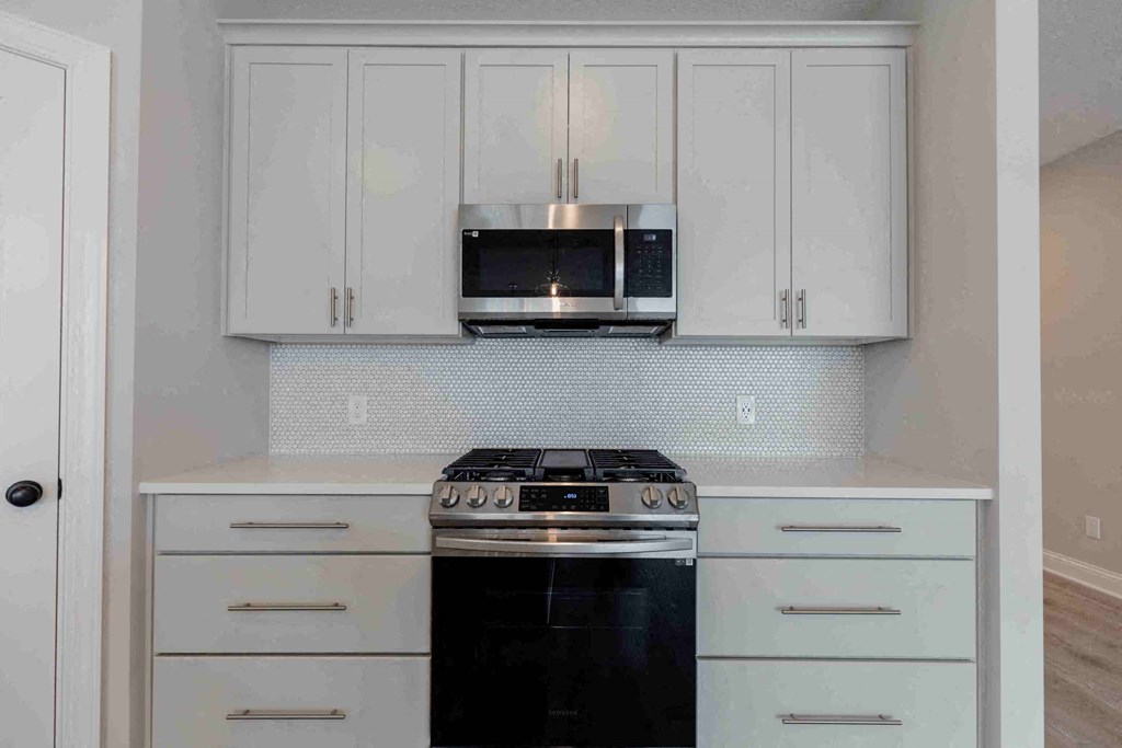 a kitchen with white cabinets and a stove and a microwave