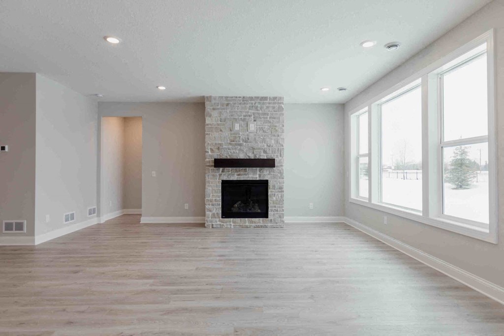 an empty living room with a fireplace and large windows