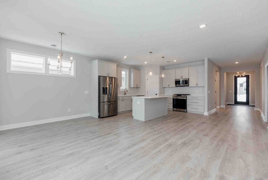 an open kitchen and living room with white walls and wood floors