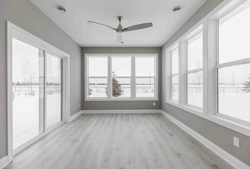 an empty living room with large windows and a ceiling fan