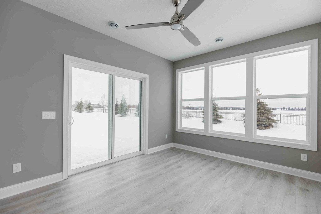an empty living room with large windows and a ceiling fan