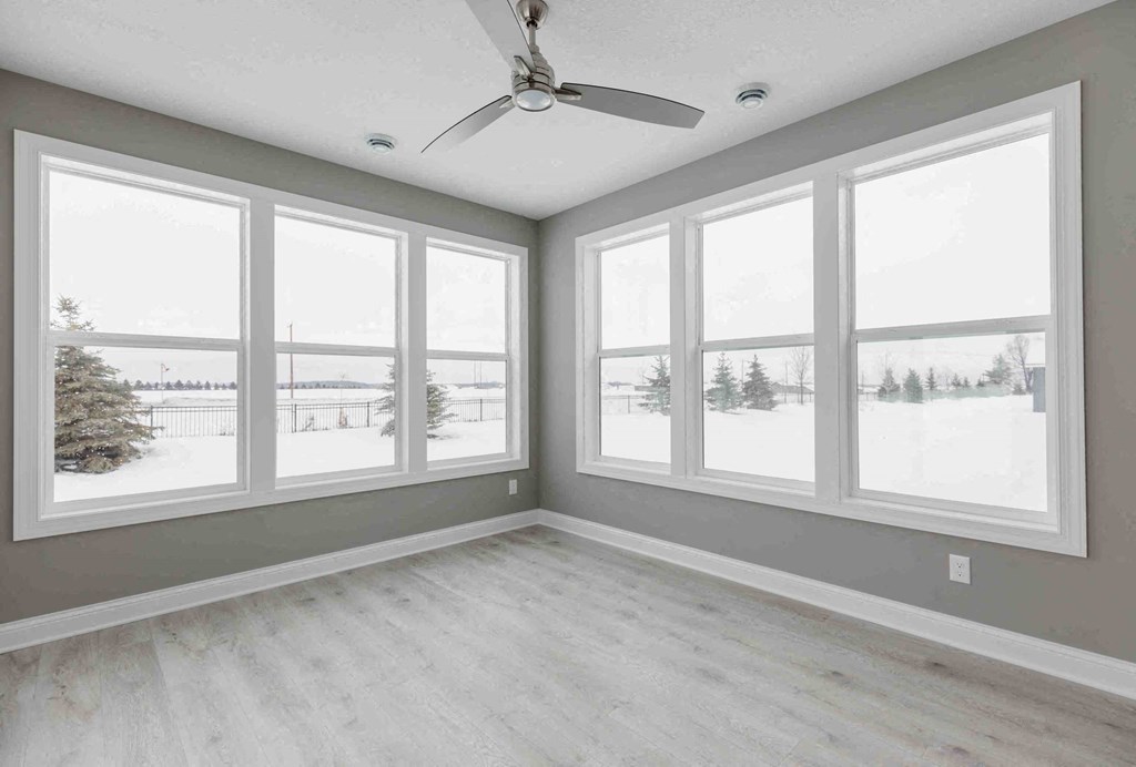 an empty living room with large windows and a ceiling fan