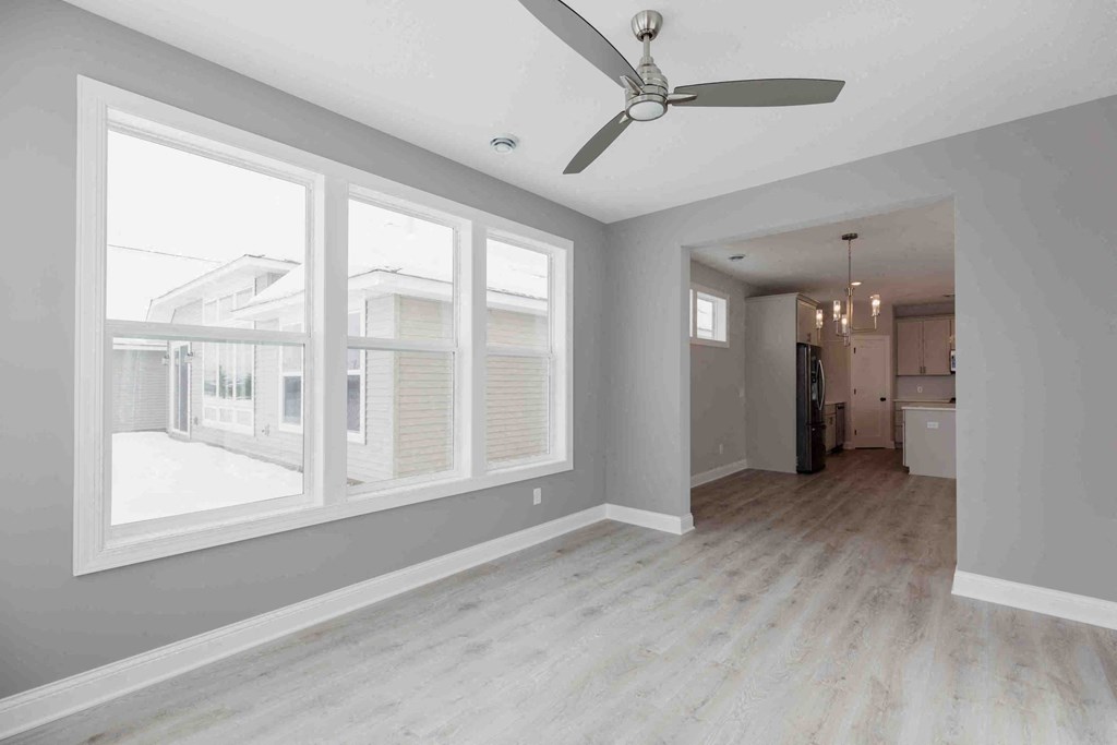 an empty living room with large windows and a ceiling fan