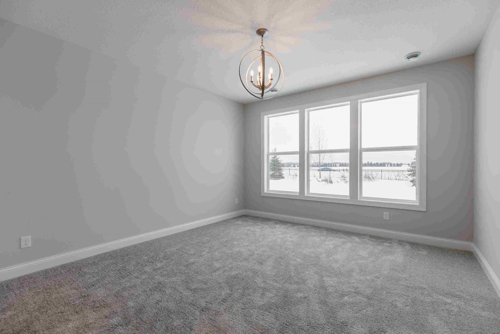 an empty living room with windows and a chandelier