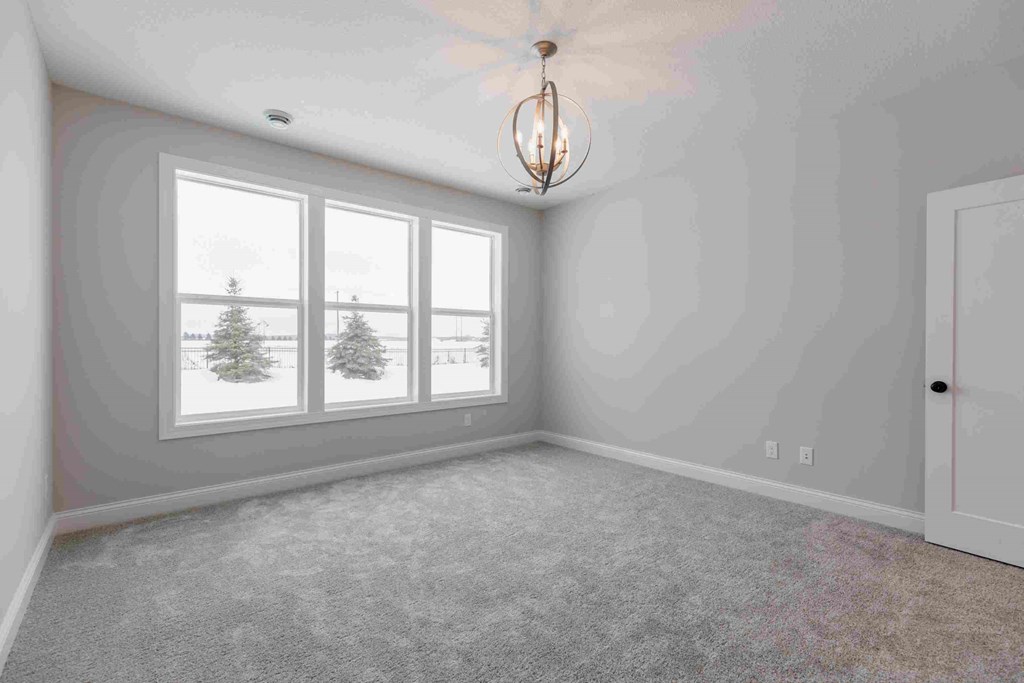 an empty living room with three windows and a door