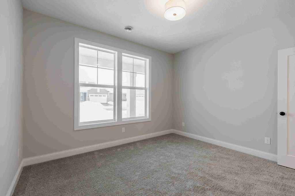 an empty living room with a window and carpet