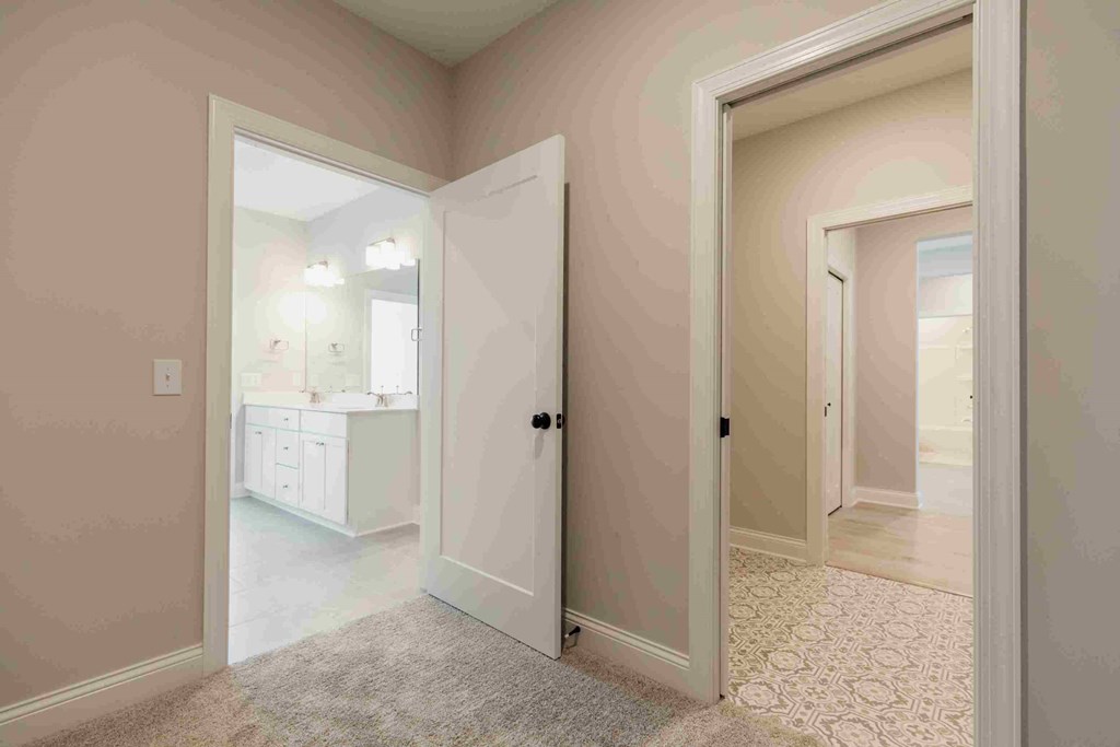 a bedroom with a door to a bathroom with a sink and a mirror