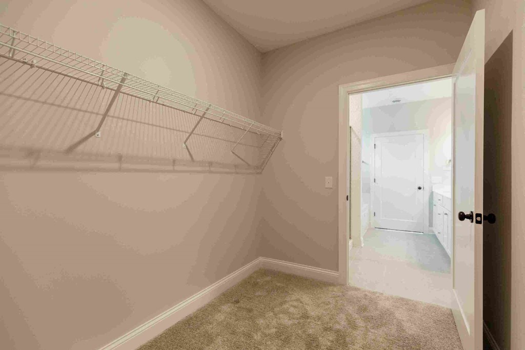 an empty closet in a bedroom with a door to the bathroom