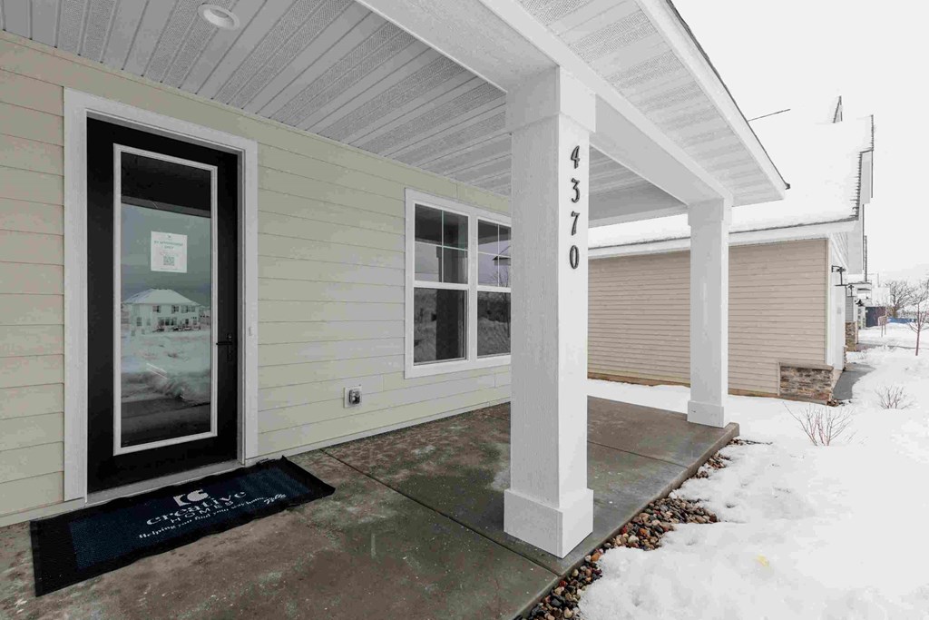 a front entrance of a home with snow on the sidewalk
