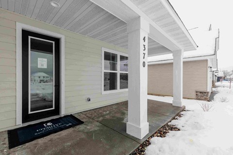 a front entrance of a home with snow on the sidewalk