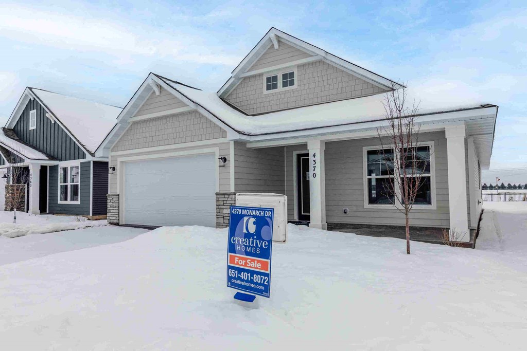 a house for sale with a for sale sign in the snow