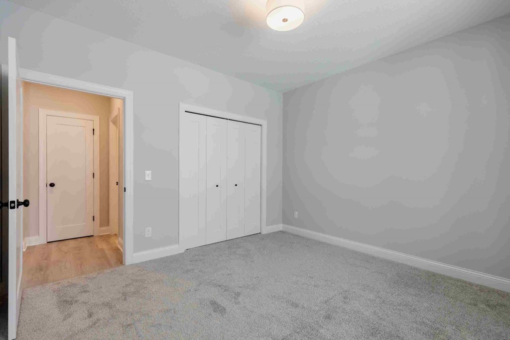 an empty bedroom with white walls and a door to a closet