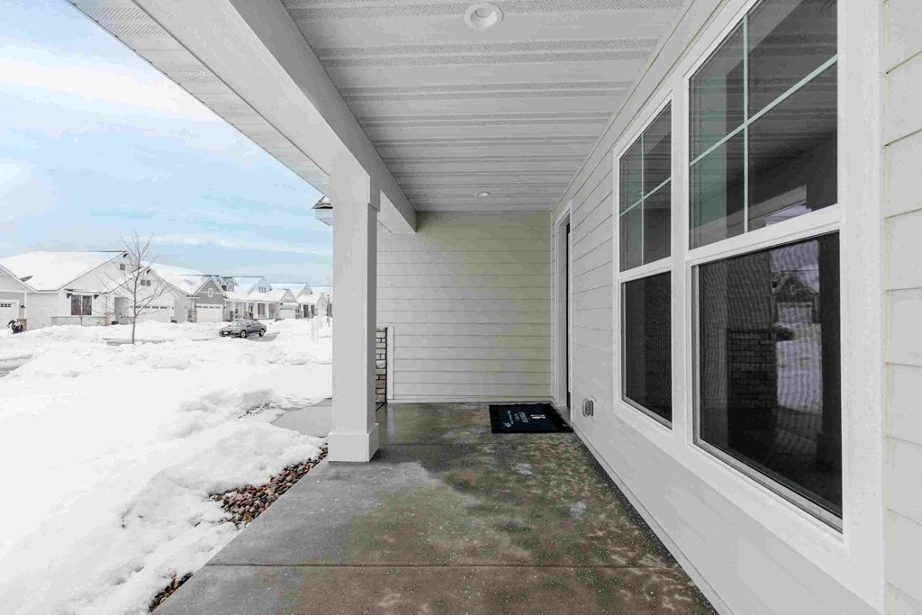 a covered porch in front of a house in the snow