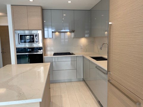 A modern kitchen with a marble countertop and stainless steel appliances.