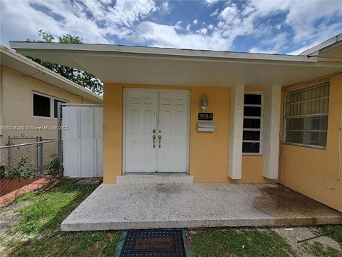 A yellow house with a white door and a small porch.