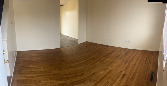 an empty living room with wooden floors and white walls