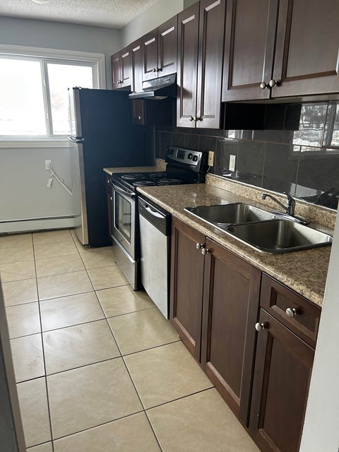A kitchen with brown cabinets and a black refrigerator.